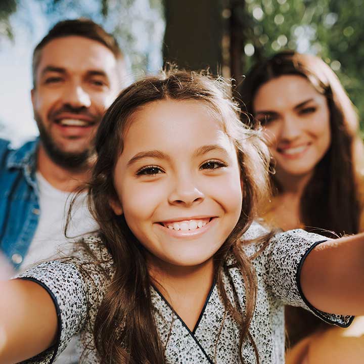 smiling girl with parents in background